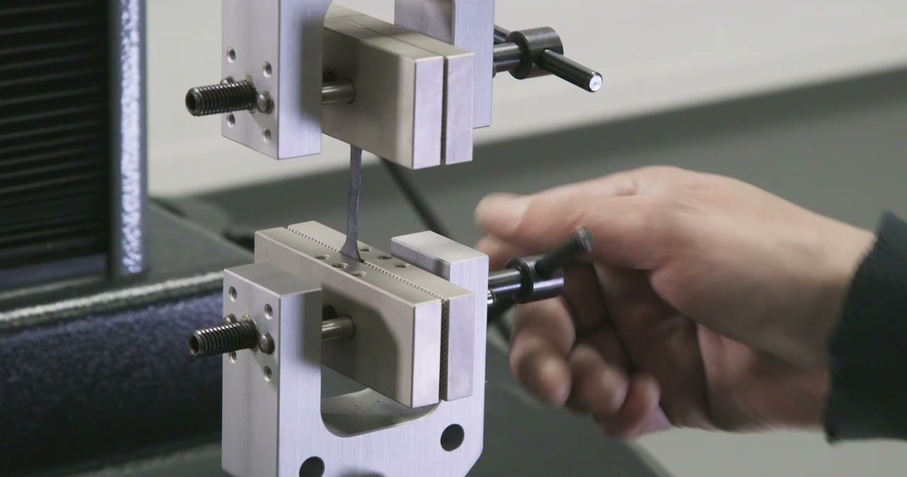 Hand stellt die Klemme der Prüfmaschine ein
